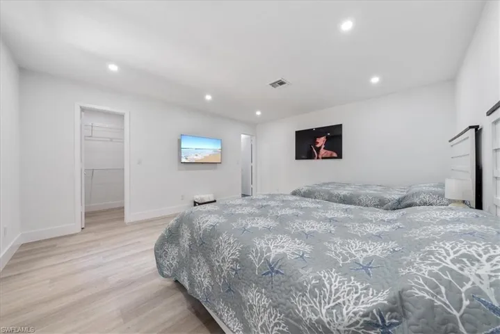 Bedroom featuring light wood finished floors, a walk in closet, and recessed lighting