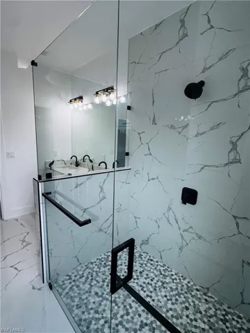 Full bath featuring baseboards, marble finish floor, and a marble finish shower
