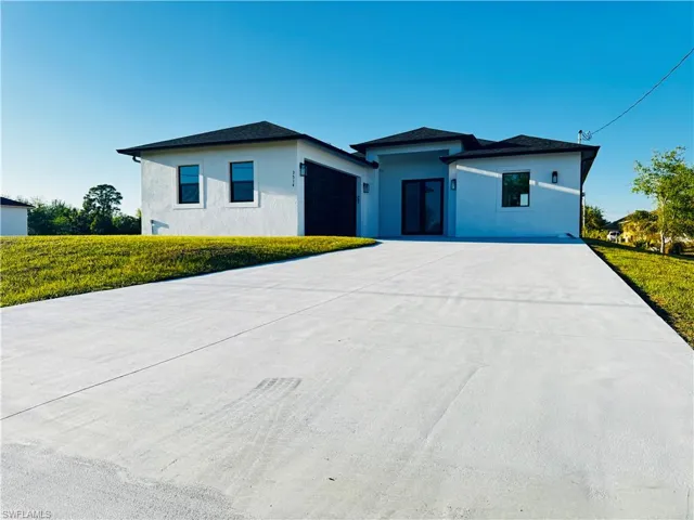 View of front facade with stucco siding, concrete driveway, and a garage