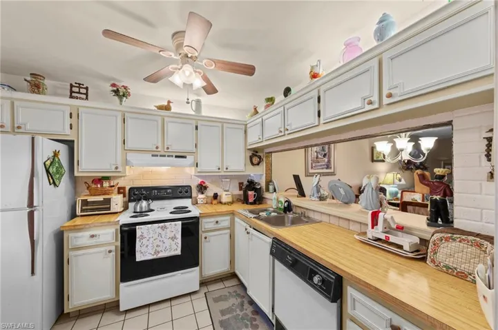 Kitchen with white appliances, light countertops, ceiling fan, and light tile patterned floors