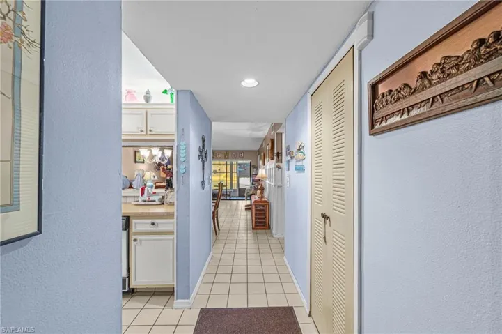 Hall with a textured wall, light tile patterned floors, and recessed lighting