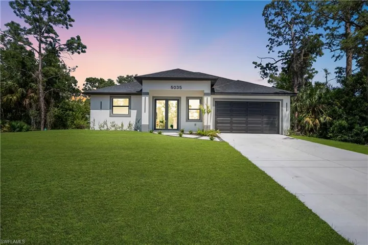 Contemporary single-story residence featuring a dark asphalt shingle roof, a two-car garage with a dark panel door, and a light-colored stucco exterior