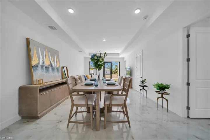 Open-concept living space featuring high ceilings with recessed lighting, large format tile flooring, and a dining area with a built-in buffet