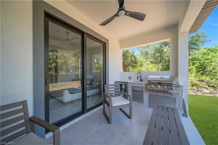 Covered patio featuring an outdoor kitchen with built-in grill, beverage refrigerator, and sink