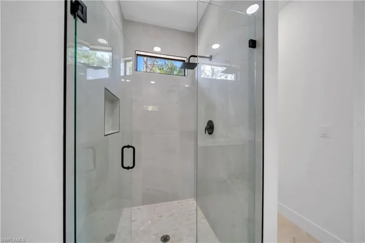 Glass-enclosed shower with matte black fixtures and a built-in niche