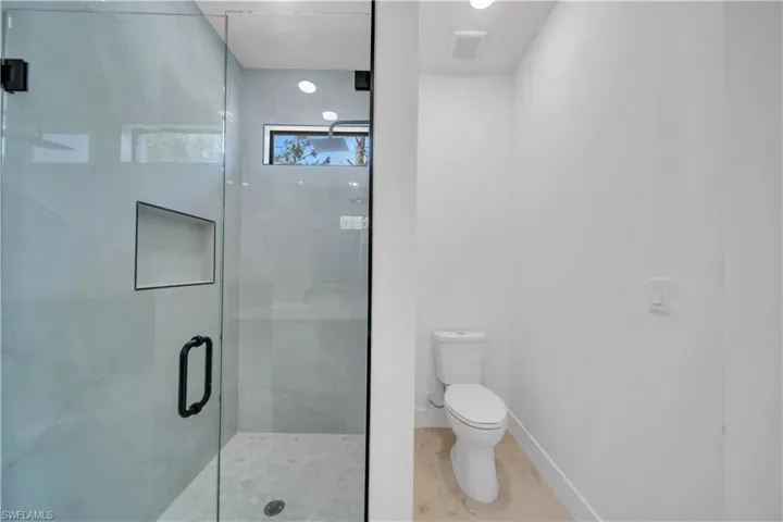 Walk-in shower with clear glass enclosure and matte black hardware