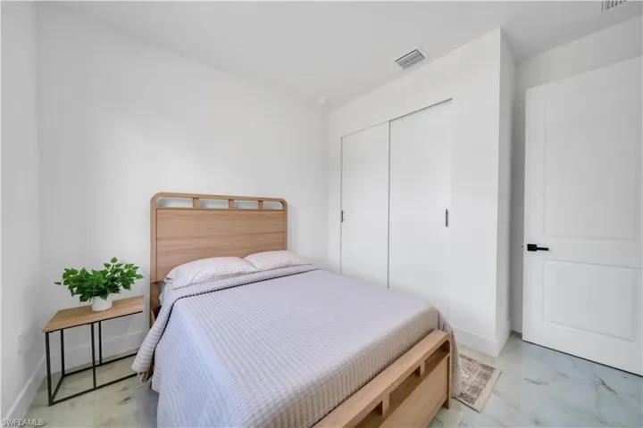 Bedroom featuring white walls, a built-in closet with sliding doors, a paneled door with matte black hardware, and light-colored flooring