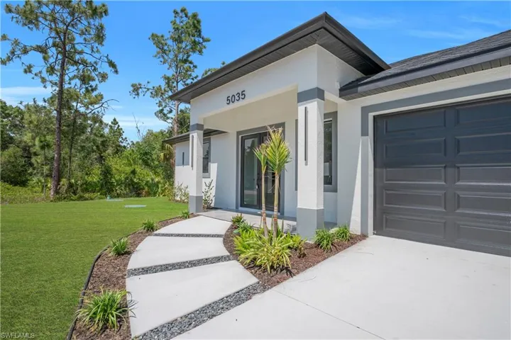 Contemporary exterior featuring a covered entry, modern garage door, and a decorative concrete pathway with gravel accents