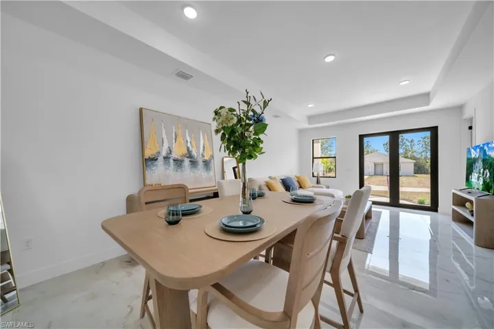 Dining area featuring polished tile flooring and a tray ceiling with recessed lighting
