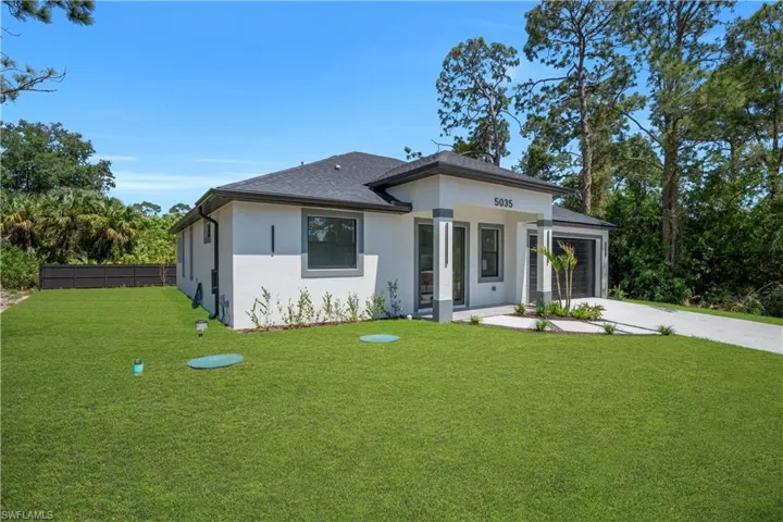 Contemporary stucco exterior with a dark shingle roof, integrated garage, and a concrete driveway