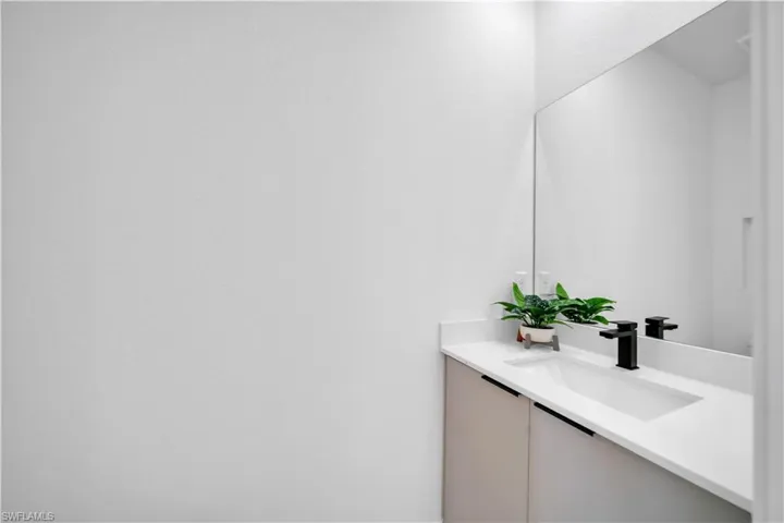 Modern vanity featuring a sleek white countertop, integrated sink, and matte black faucet