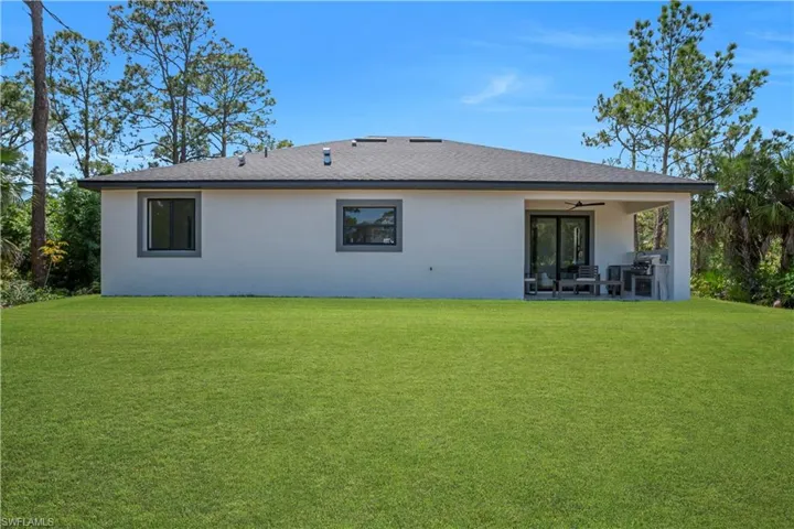 Expansive green lawn with a contemporary single-story home featuring a covered patio