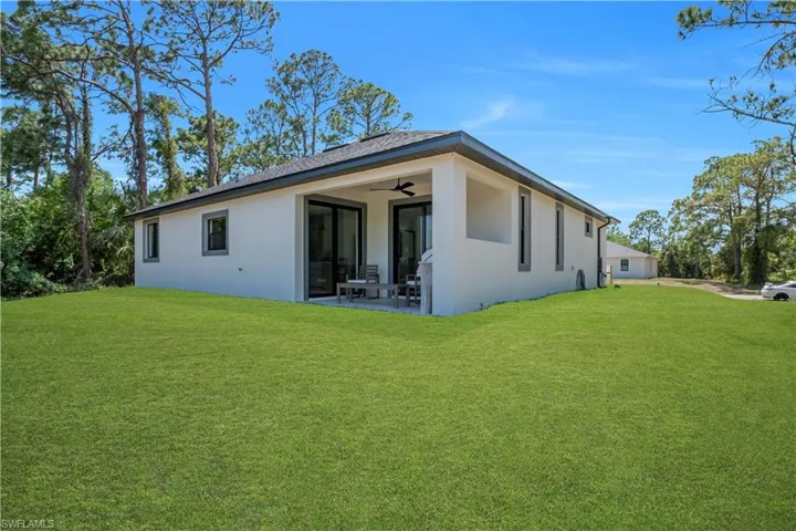 Expansive green lawn surrounds a contemporary residence with a covered patio