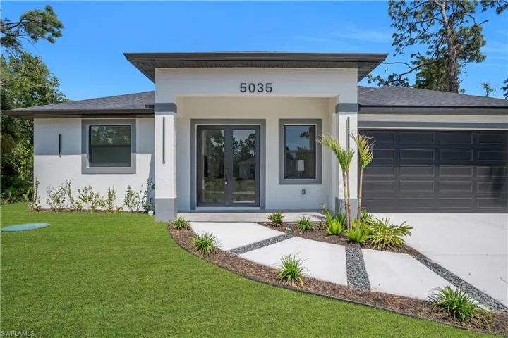 Modern stucco exterior featuring a flat roofline over the entryway, dual pane windows, and a segmented dark garage door