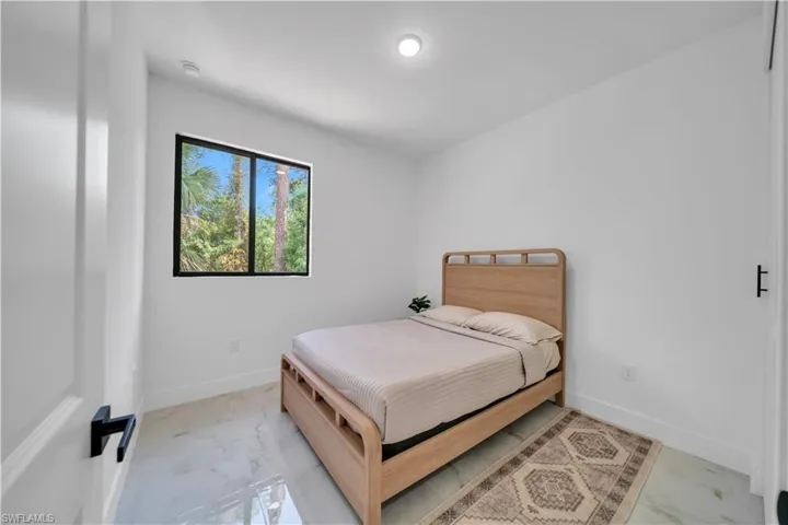 Bright room featuring a single window with a black frame, high ceilings with recessed lighting, and white baseboards