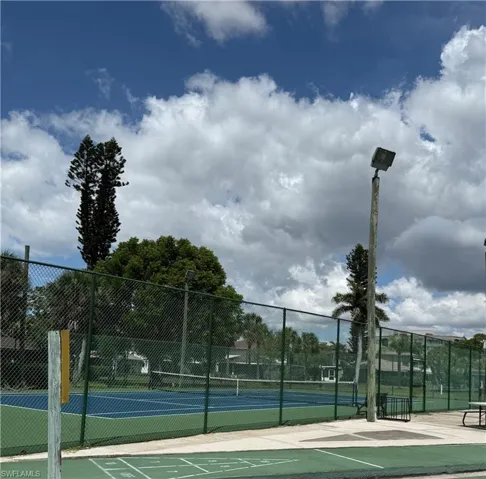 Regulation-size tennis court with a blue playing surface and green surrounding area