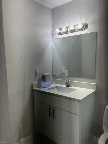Bathroom vanity featuring a white cabinet with dark hardware, an integrated sink, and a light-toned countertop
