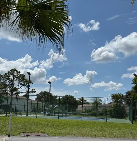 Tennis court featuring perimeter fencing and court lighting