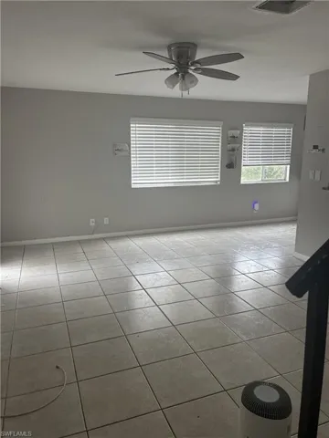 Spacious room featuring neutral-toned walls and large square tile flooring