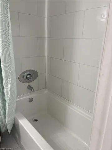 Bathtub with chrome fixtures and white tiled surround