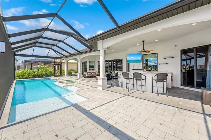 View of pool with a bar, a lanai, a patio area, and ceiling fan