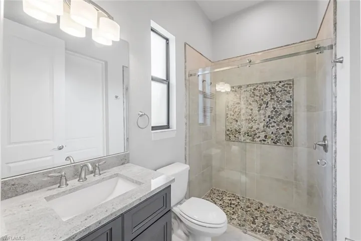 Bathroom with a shower with door, a healthy amount of sunlight, and toilet