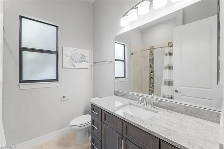 Bathroom with toilet, tile floors, and large vanity