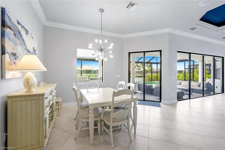 Dining area with crown molding, light tile floors, and a chandelier