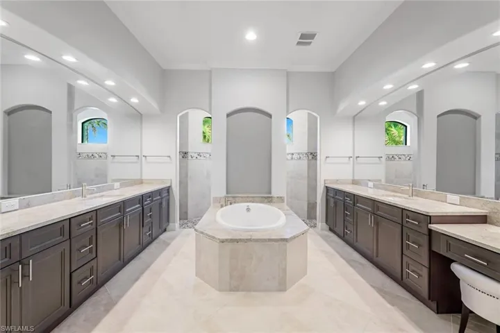 Bathroom with tile floors, tiled tub, and vanity