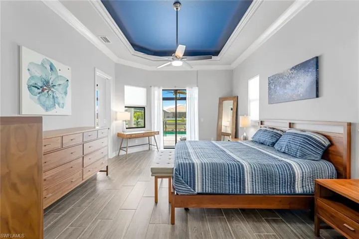 Bedroom with a tray ceiling, hardwood / wood-style flooring, ceiling fan, and access to exterior