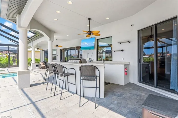 View of patio featuring ceiling fan, a swimming pool, and a bar