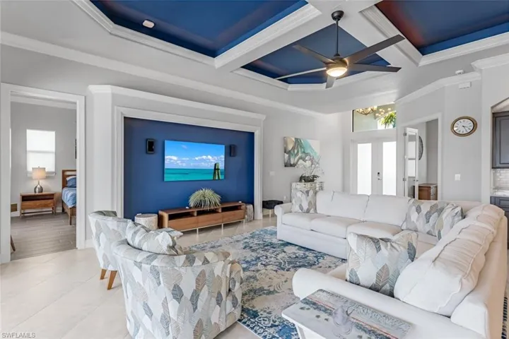 Living room with ornamental molding, ceiling fan, a tray ceiling, and coffered ceiling