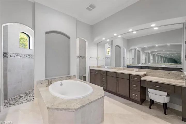 Bathroom with crown molding, tile flooring, tiled tub, and vanity