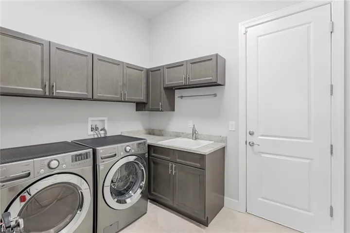 Laundry room with cabinets, light tile flooring, hookup for a washing machine, washer and dryer, and sink