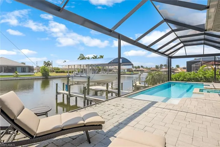 View of swimming pool with a dock, a patio area, a lanai, and a water view