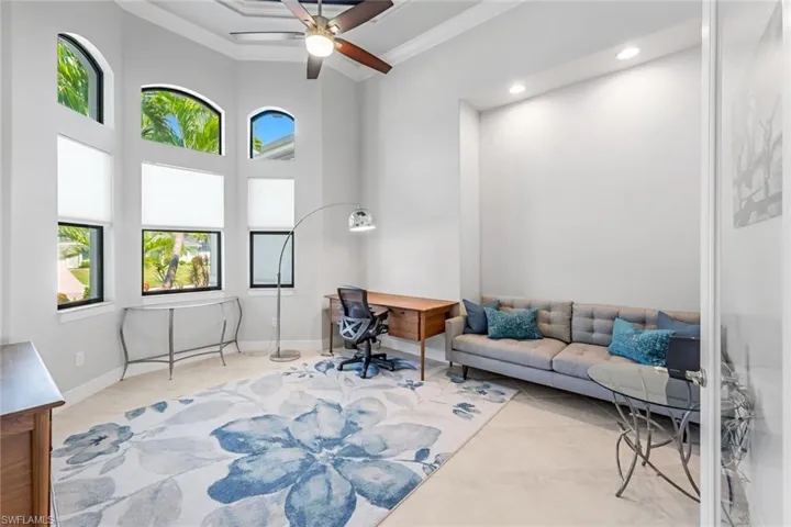 Living room featuring a towering ceiling, ornamental molding, and ceiling fan
