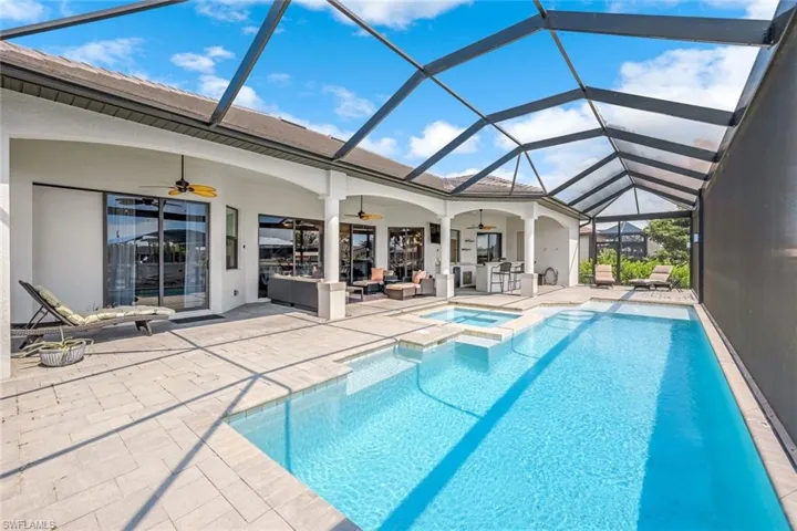 View of swimming pool with ceiling fan, glass enclosure, an in ground hot tub, and a patio