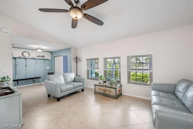 Living room with vaulted ceiling, ceiling fan, and light tile patterned flooring