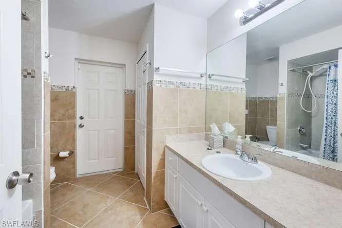 Bathroom featuring tile walls, vanity, tile patterned floors, and toilet