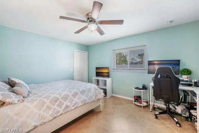 Tiled bedroom with ceiling fan and a closet