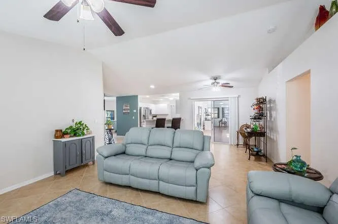 Tiled living room featuring vaulted ceiling and ceiling fan