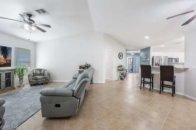 Tiled living room with ceiling fan and lofted ceiling