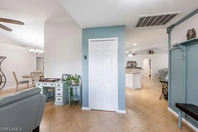 Office featuring vaulted ceiling, ceiling fan with notable chandelier, and light tile patterned floors