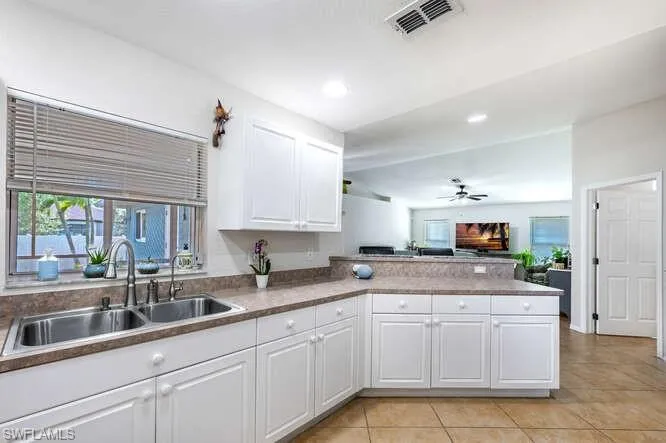 Kitchen with sink, white cabinetry, light tile patterned floors, kitchen peninsula, and ceiling fan