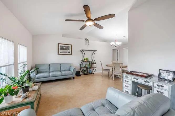 Living room with ceiling fan with notable chandelier and vaulted ceiling