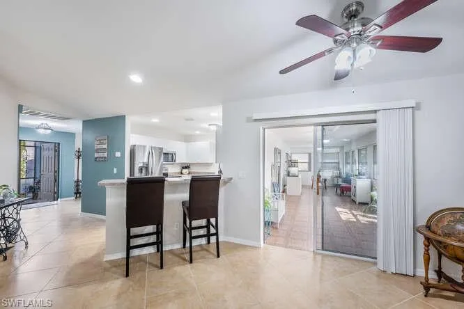 Kitchen with appliances with stainless steel finishes, white cabinetry, a kitchen breakfast bar, light tile patterned flooring, and kitchen peninsula