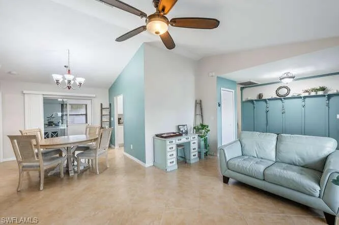 Living room featuring lofted ceiling and ceiling fan with notable chandelier