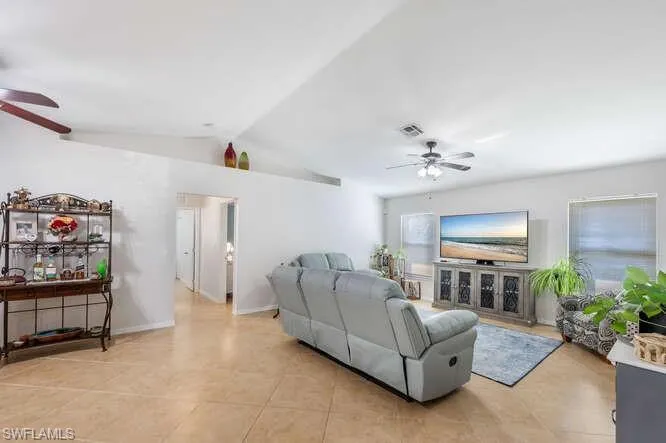 Living room featuring lofted ceiling, light tile patterned floors, and ceiling fan