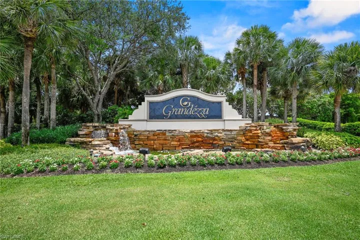Community sign with a yard and view of wooded area