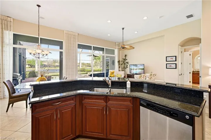 Kitchen featuring light tile patterned flooring, dishwasher, and dark stone countertops